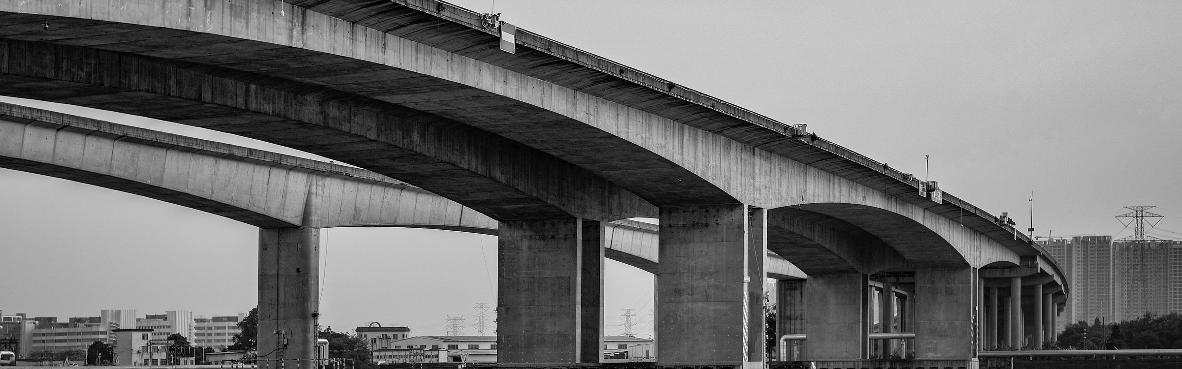 A multi-lane road bridge curving away over open water on tall concrete piers